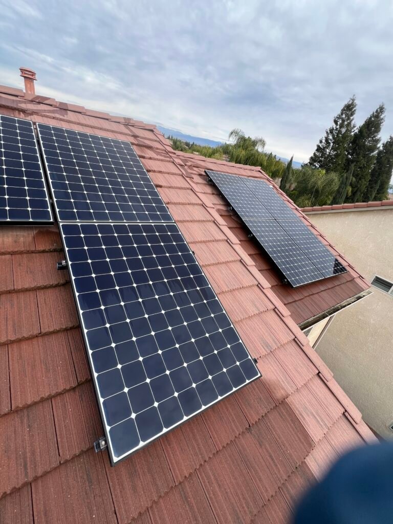 Edge of a rooftop solar panel on a red tile roof where pigeons nest