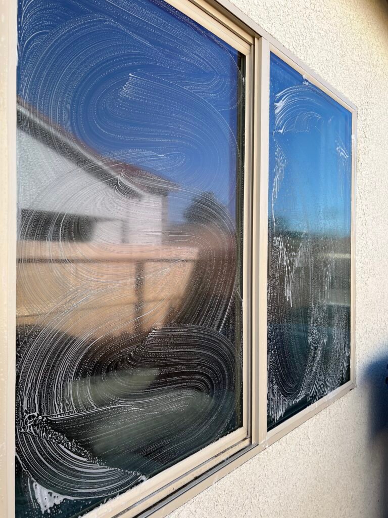 Window mid-cleaning with soap swirls on the glass
