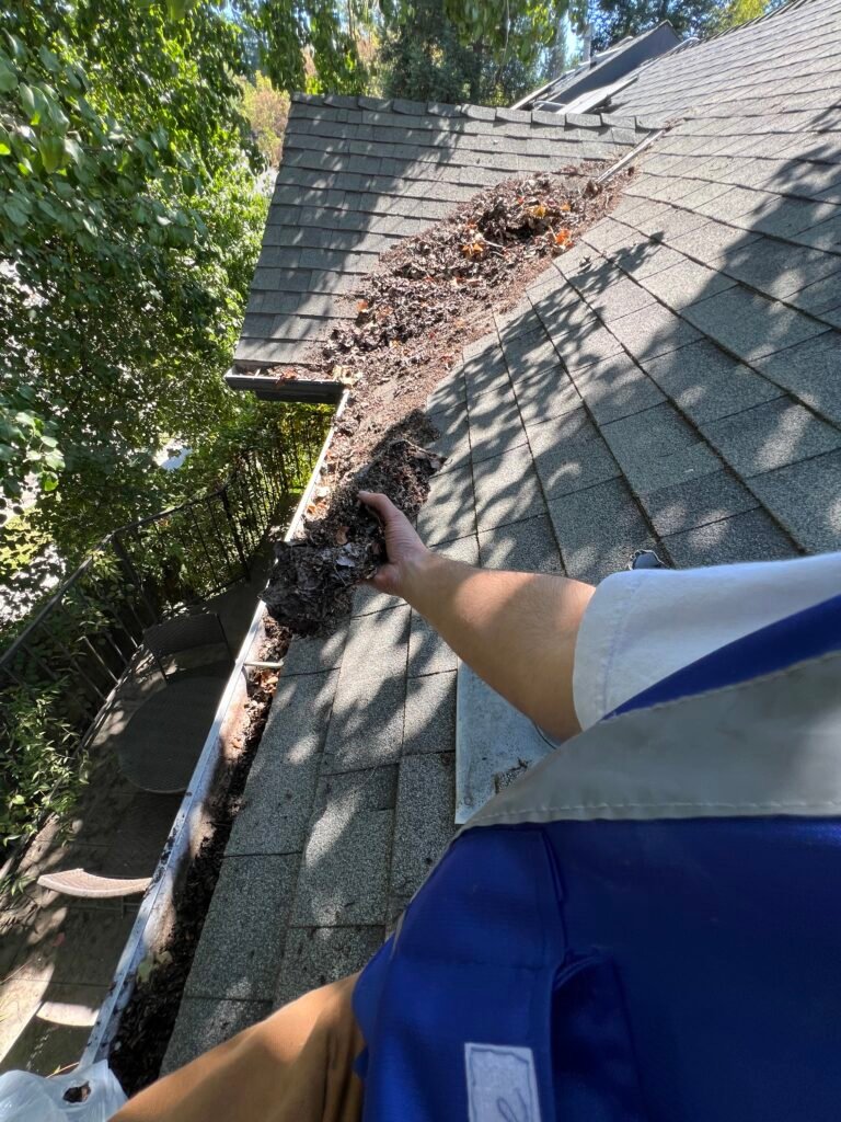 Ducky's technician removing debris from a gutter by hand
